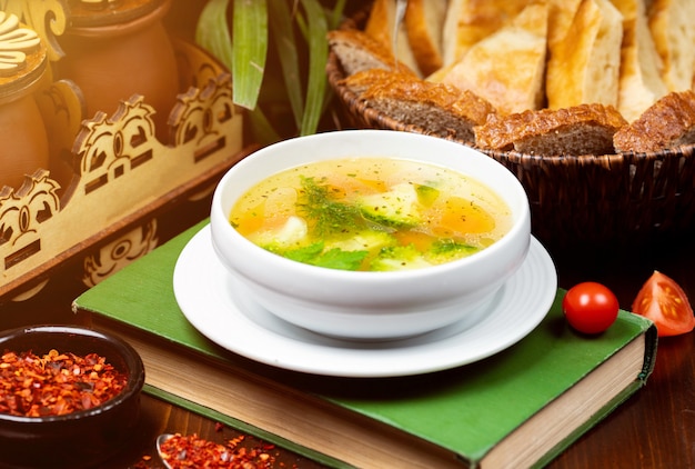 Homemade chicken vegetable soup, overhead view on a book on the table 