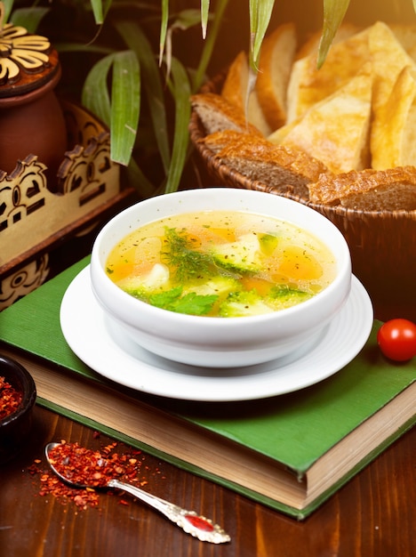 Homemade chicken vegetable soup, overhead view on a book on the table