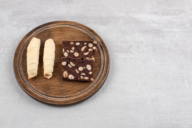 Homemade chocolate brownies and roll cookie on a board, on the marble table