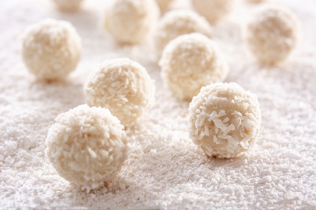 Homemade coconut balls on white wooden table