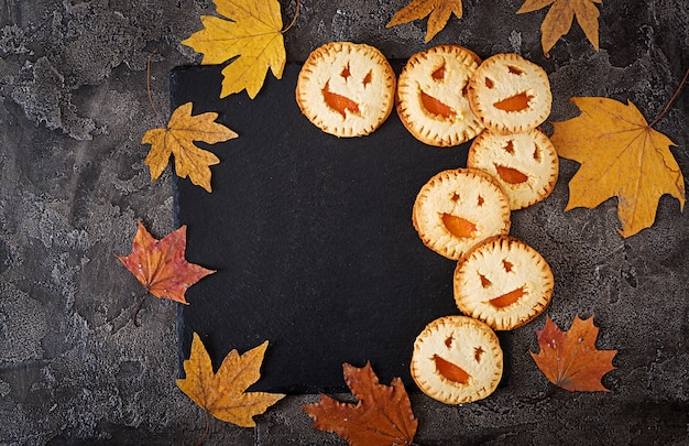 Free Photo homemade  cookies in the form as halloween  jack-o-lantern pumpkins  on the dark table. top view.