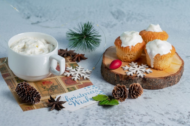 Homemade creamy muffins on wooden surface with hot chocolate .