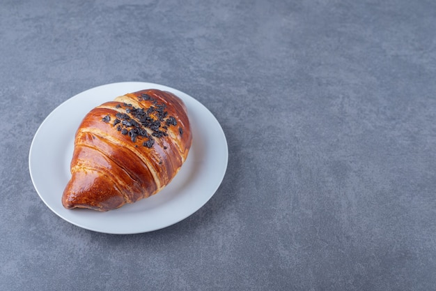 Homemade croissant with chocolate on a plate , on the marble.