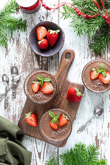 Homemade delicious chocolate mousse or panna cotta with berries on a white stone or wooden background Festive dessert Vertical