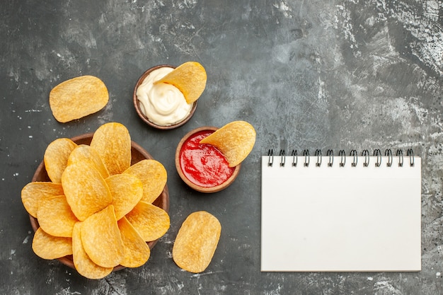 Free Photo homemade delicious potato chips mayonnaise with ketchup and notebook on gray table 