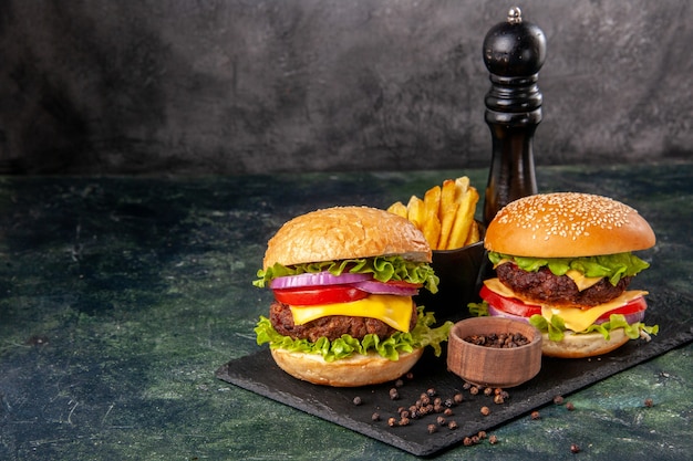 Homemade delicious sandwiches on black cutting board fries pepper on dark gray blurred surface