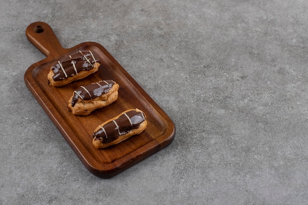 Free photo homemade fresh chocolate eclairs on wooden cutting board