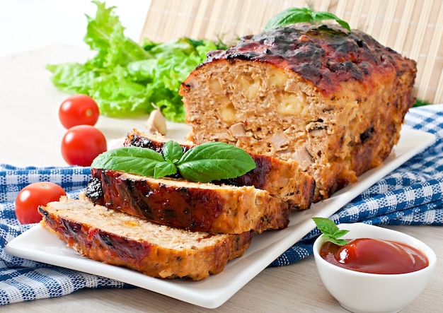 Homemade ground meatloaf with ketchup and basil