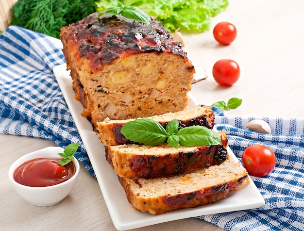 Homemade ground meatloaf with ketchup and basil