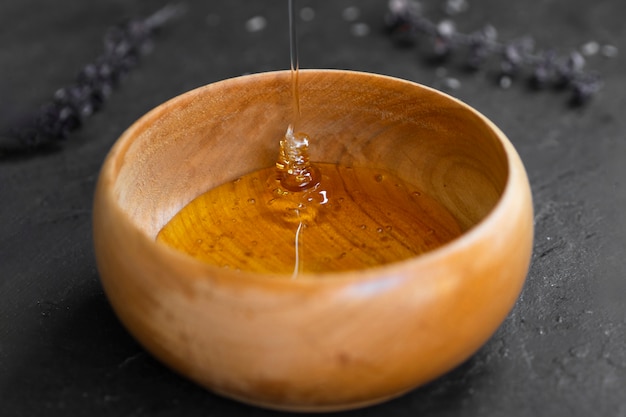 Homemade honey pouring in wooden bowl