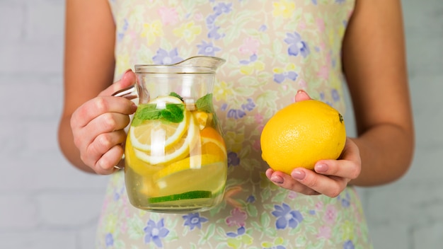 Free photo homemade lemonade and lemon held by a woman