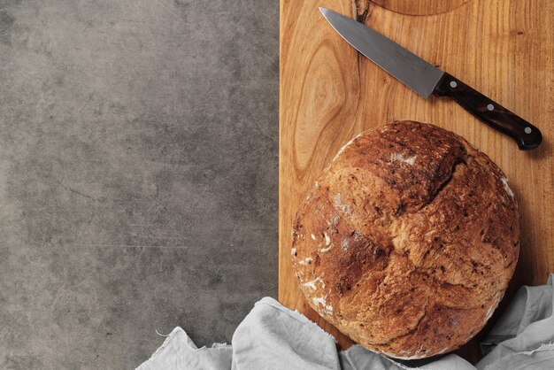 Homemade loaf of artisan sourdough bread on a cutting board next to a knife on a gray concrete background View of reconciliation with space for text