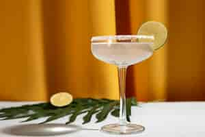 Free photo homemade margarita drink with lime and palm leaf on table against yellow curtain