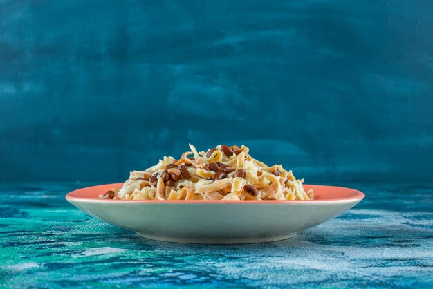 Homemade noodles with beans on a plate on trivet , on the blue table. 