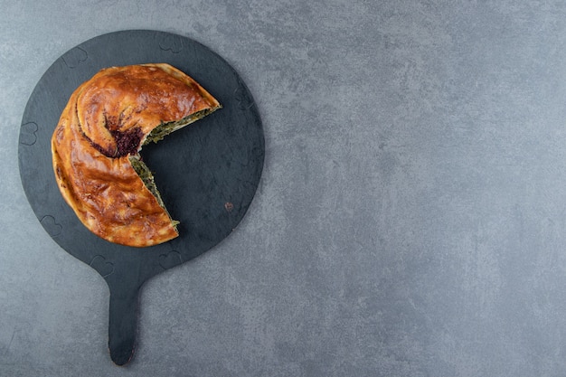 Free photo homemade pie stuffed with greens on black cutting board.