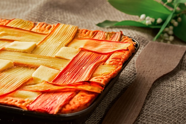 Homemade rhubarb pie on a table with rough linen bedding closeup horizontal layout selective focus on a freshly baked tart