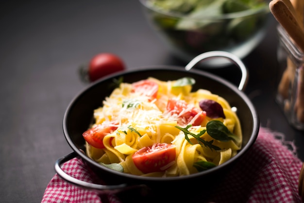 Free photo homemade spaghetti pasta with grated cheese and cherry tomatoes in container