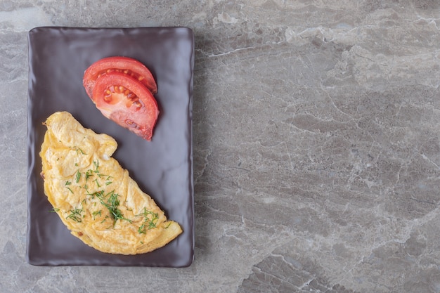 Free Photo homemade tasty omelette with tomato on dark plate.