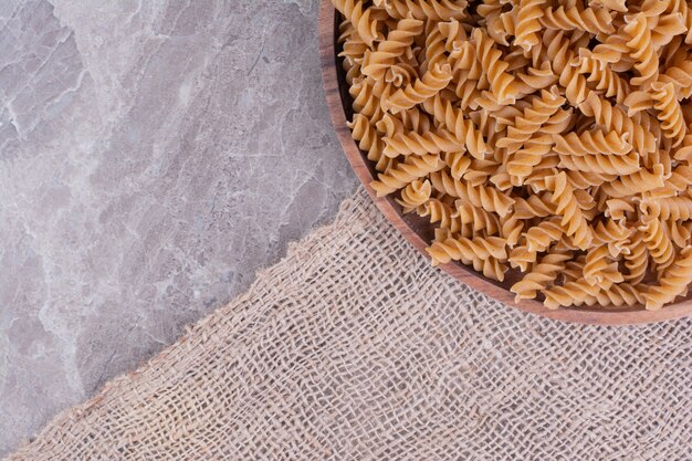 Homemade uncooked pastas in a wooden platter on rustic surface