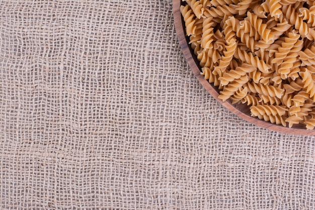 Homemade uncooked pastas in a wooden platter on rustic surface