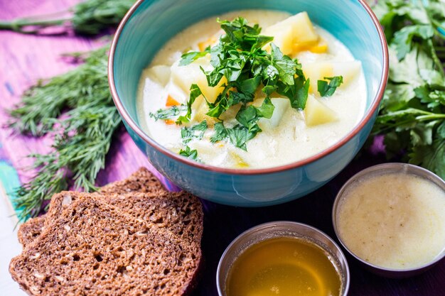 Free Photo homemade vegetarian soup with potato carrots pepper with dark bread and dill on wooden background