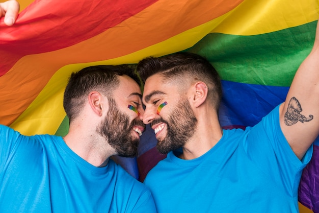 Free Photo homosexual couple gently cuddling on rainbow flag