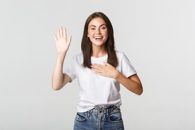 Honest smiling cute girl telling truth, raising hand to make promise.