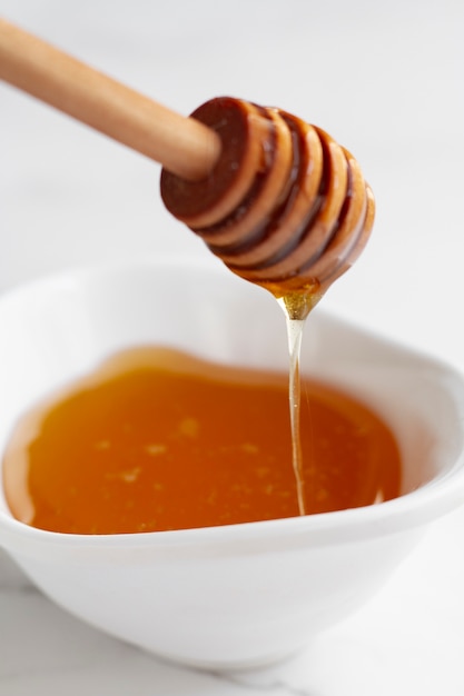 Free photo honey in bowl with wooden honey dipper