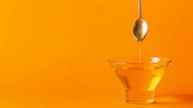 Free photo honey dripping off spoon in bowl with copy space