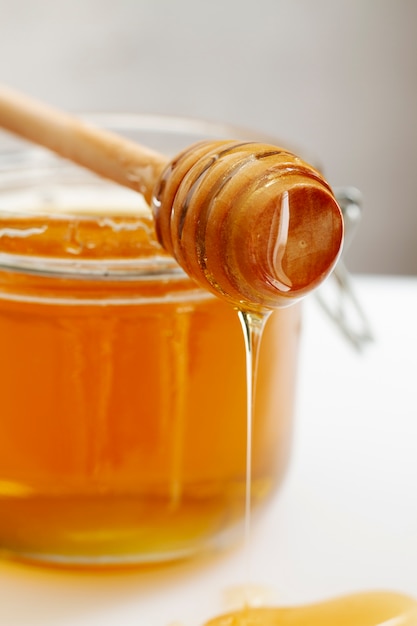 Free photo honey jar with wooden honey dipper