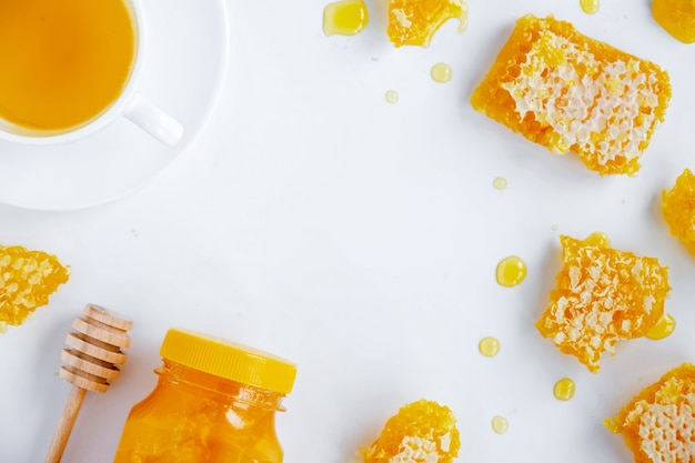 Honey products composition. Honey in jar, honeycomb, tea and special spoon. White background