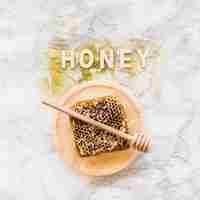 Free photo honey word over the honeycomb with dipper on wooden plate