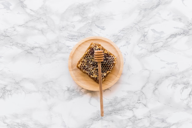 Free Photo honeycomb with honey dipper on wooden plate