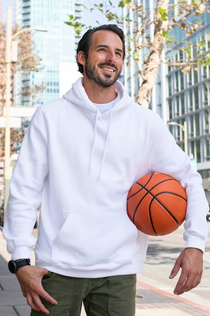 Free photo hoodie on a man with basketball in the city