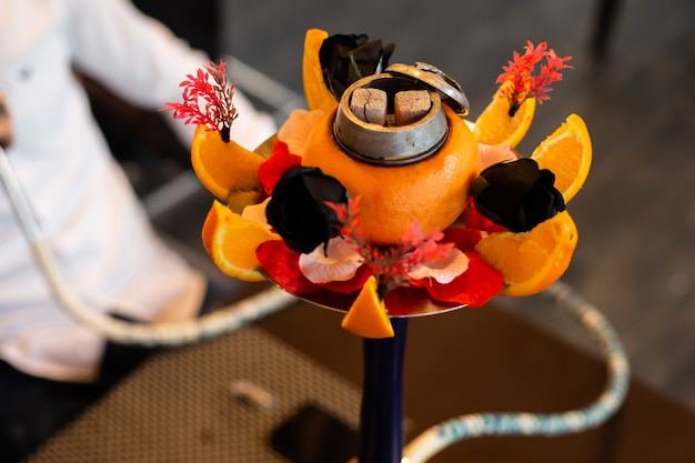 Hookah decorated with orange, black roses and other flowers