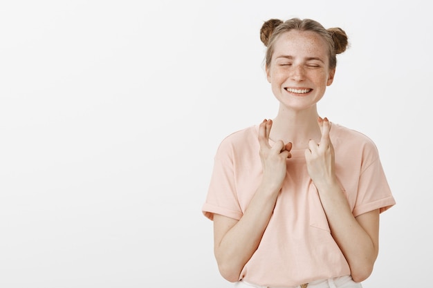 Free Photo hopeful smiling teenage girl posing against the white wall