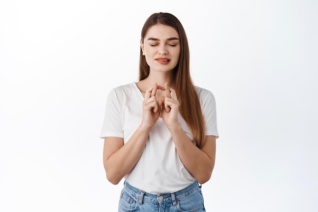 Free photo hopeful stylish girl cross fingers for luck biting lip eager to receive positive result anticipating good news fortune making wish praying begging for dream come true white background