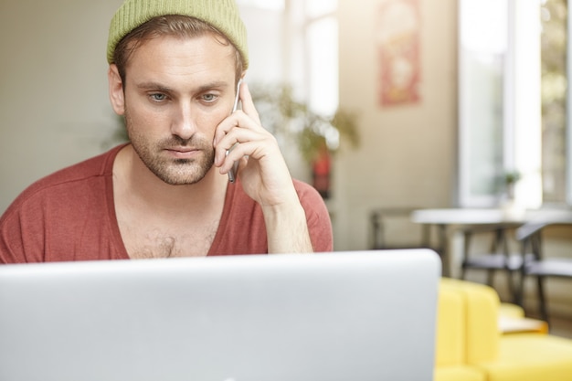 Free Photo horizonatal portrait of serious bearded man has call conversation, sits in front of generic laptop