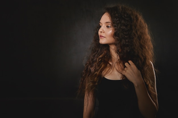 Free photo horizontal isolated image of attractive charming young brunette woman model in black top having serious facial expressions