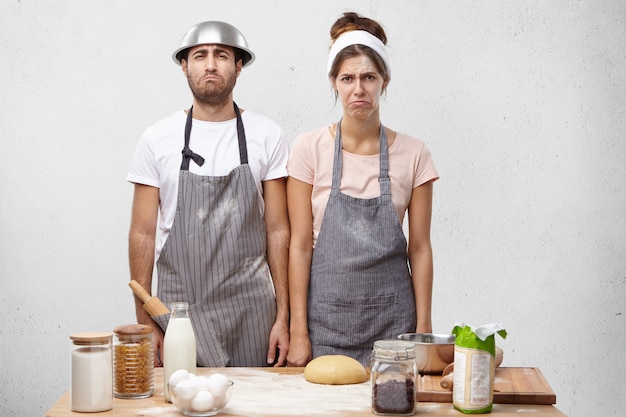 Horizontal portrait of sorrorful talented cooks curve lips and look with displeased expression