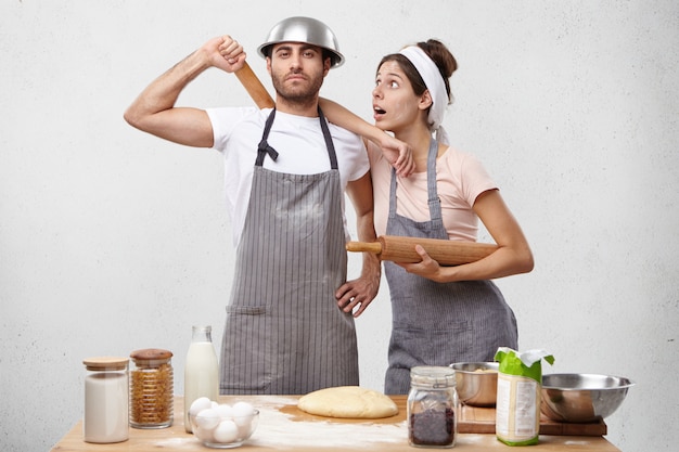 Horizontal portrait of surprised female leans at husband`s shoulder being shocked that he is not tired