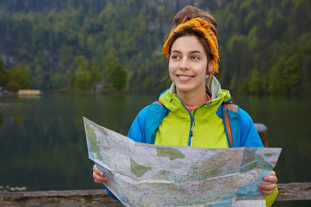 Free photo horizontal shot of active cheerful female traveler holds tourist map