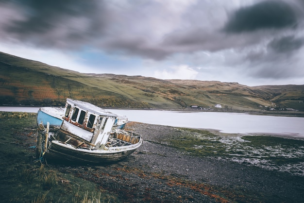 Free photo horizontal shot of a beach with an abandoned boat near the water