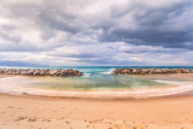 Free Photo horizontal shot of a beautiful beach with rocks under the breathtaking cloudy sky