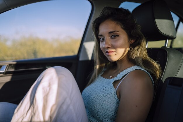 Horizontal shot of a beautiful young caucasian female posing in the front seat of a car in a field