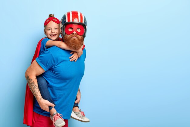 Free Photo horizontal shot of caring father gives piggyback to small child