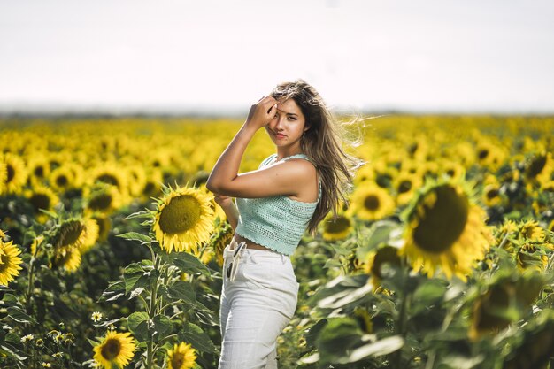 Horizontal shot of a caucasian young female posing in a bright field of sunflowers on a sunny day