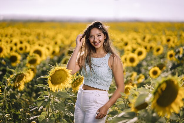 Horizontal shot of a caucasian young female posing in a bright field of sunflowers on a sunny day