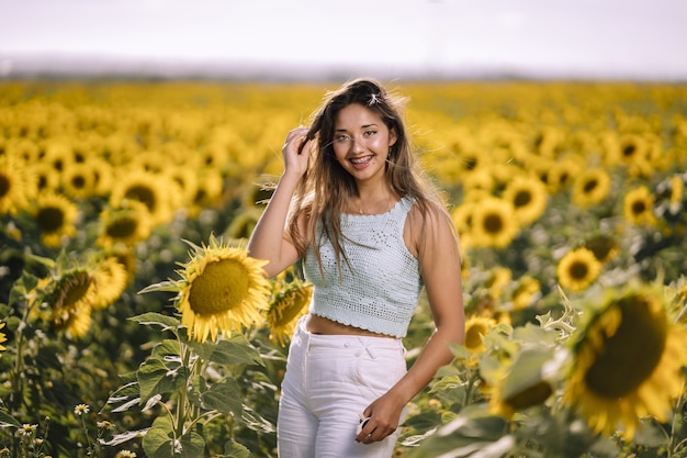 Horizontal shot of a caucasian young female posing in a bright field of sunflowers on a sunny day