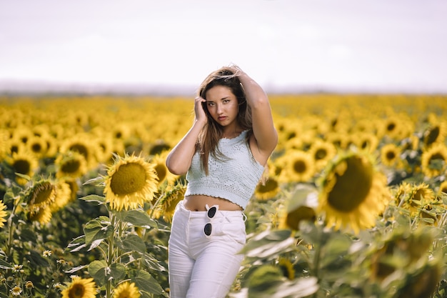 Horizontal shot of a caucasian young female posing in a bright field of sunflowers on a sunny day